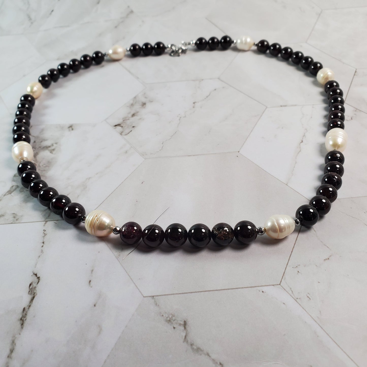 Necklace with Garnet and white beads on a marble surface