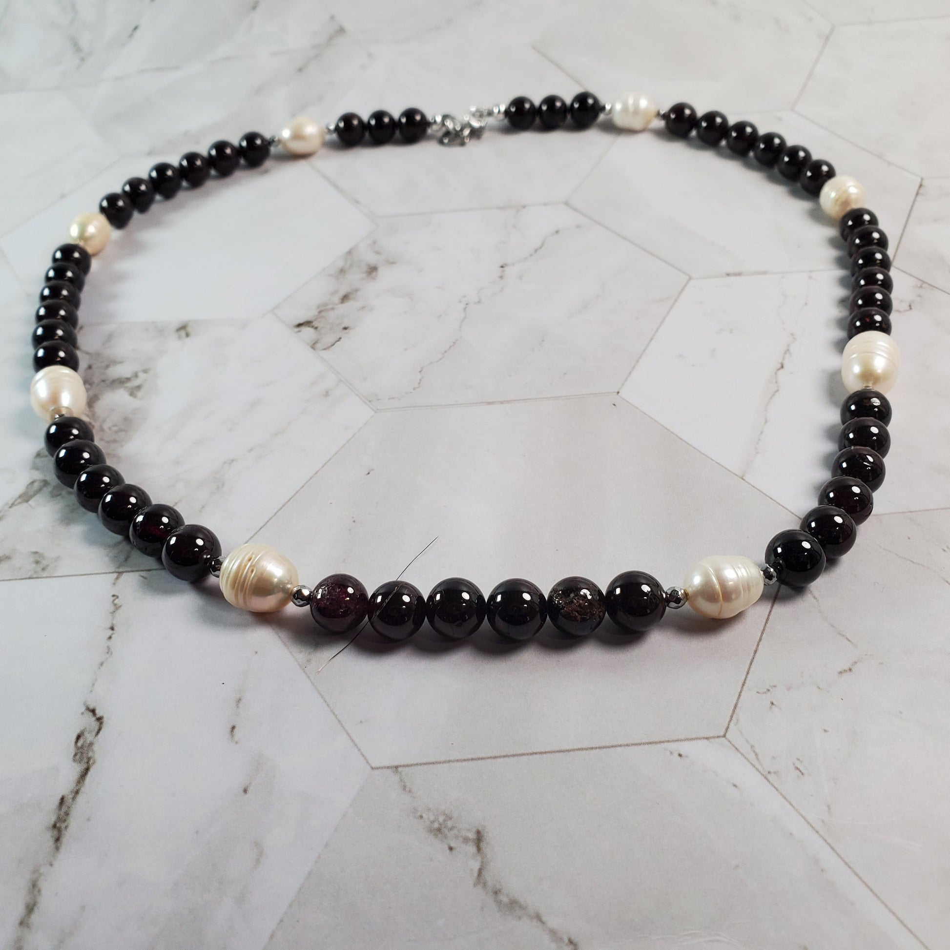 Necklace with Garnet and white beads on a marble surface