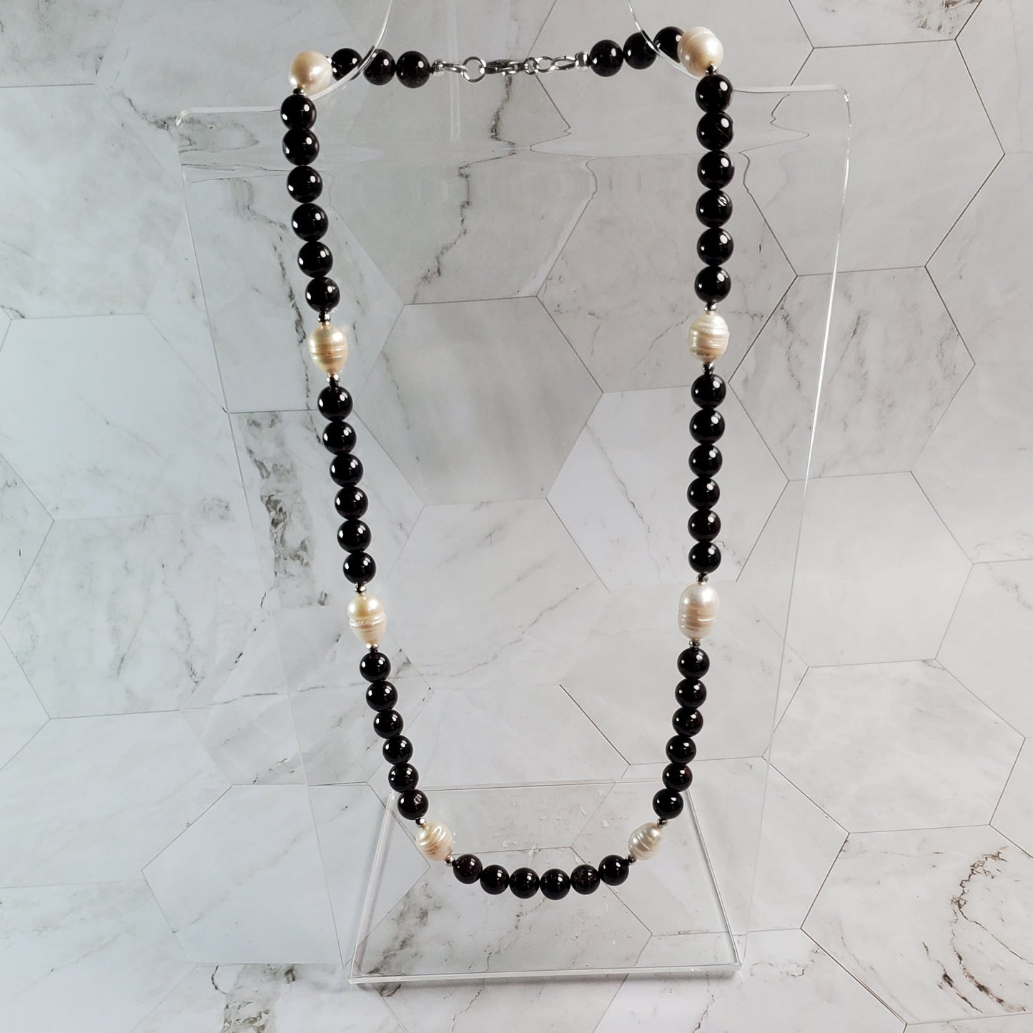 Garnet and white beaded necklace on a marble wall