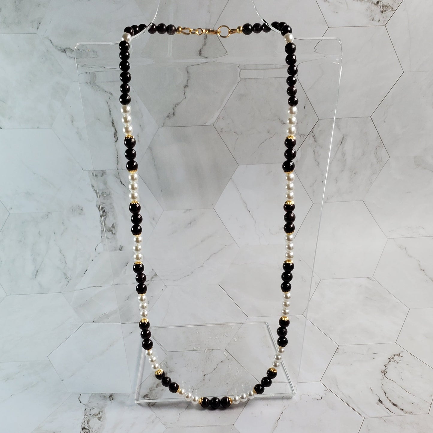 Necklace with Garnet and gold beads on a marble surface