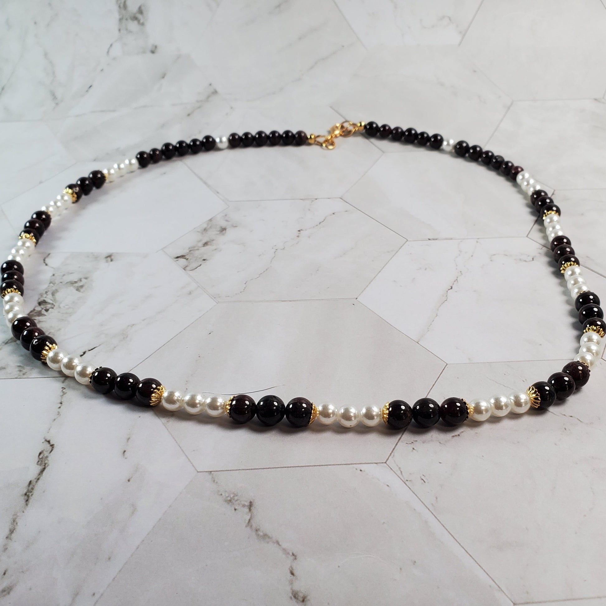Necklace with Garnet and white beads on a marble surface
