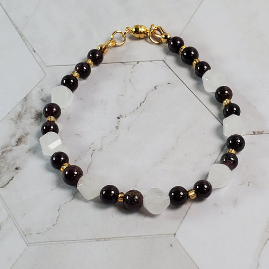 Bracelet with red, pink and gold beads on a marble surface