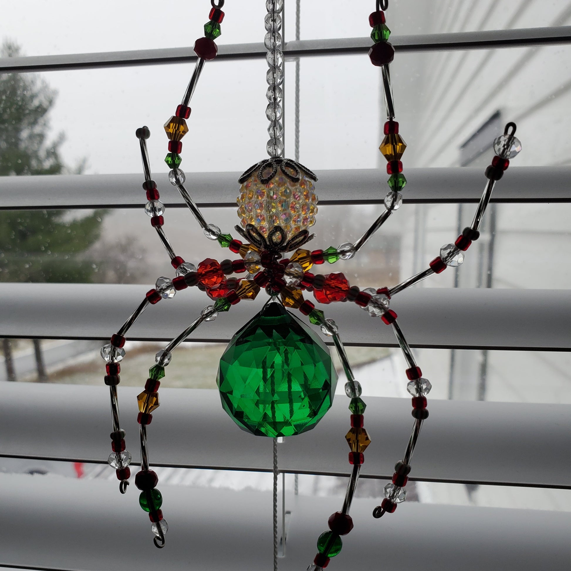 Decorative spider with beads and a green center on a white background