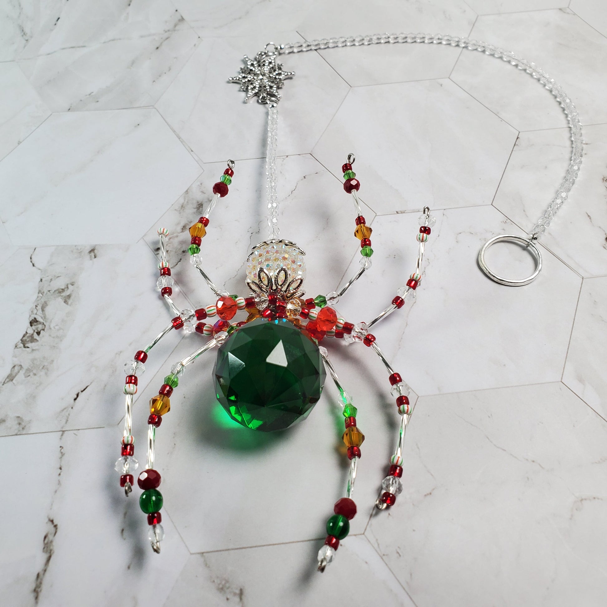 Decorative spider with a green gem on a marble surface