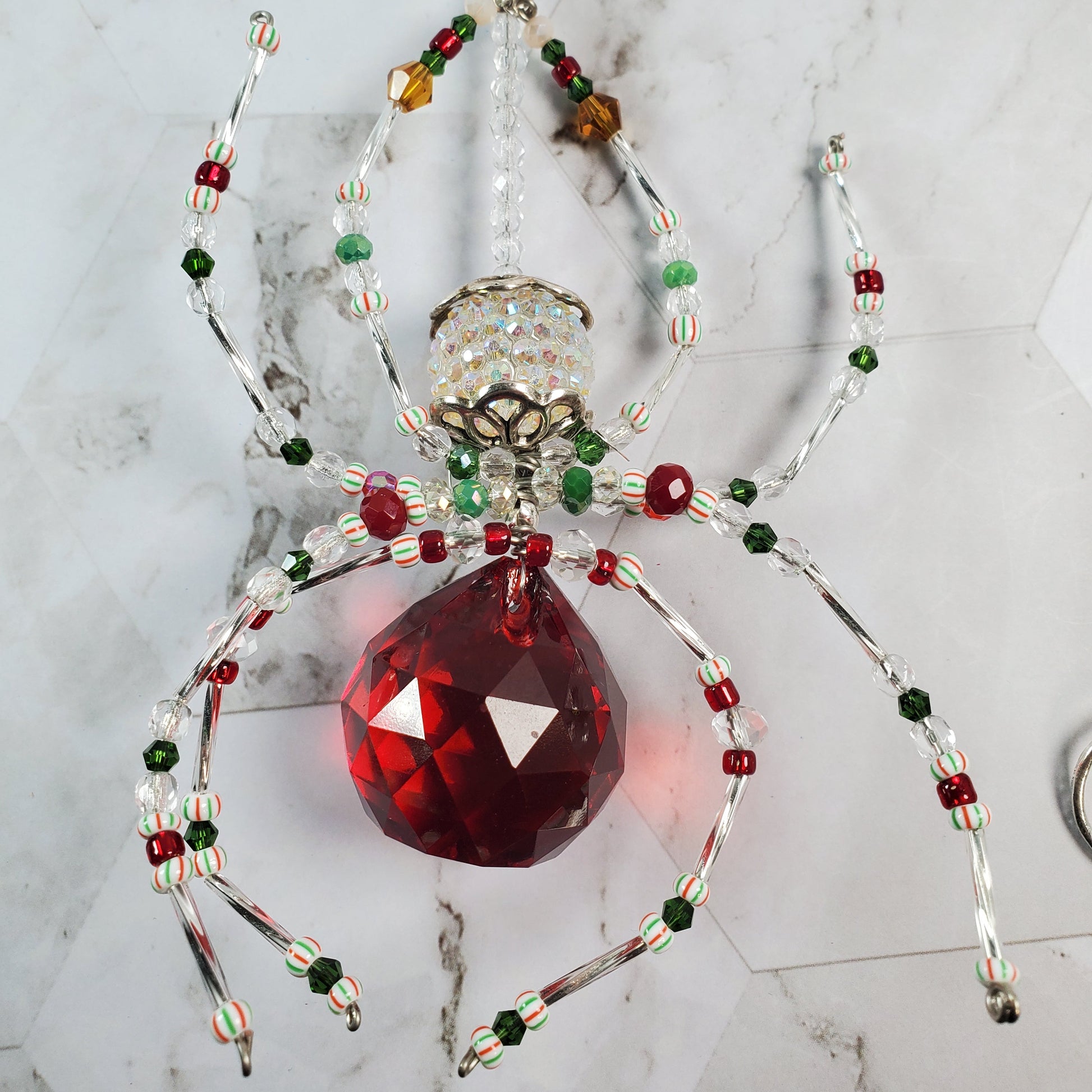 Decorative spider with red crystal on a marble surface