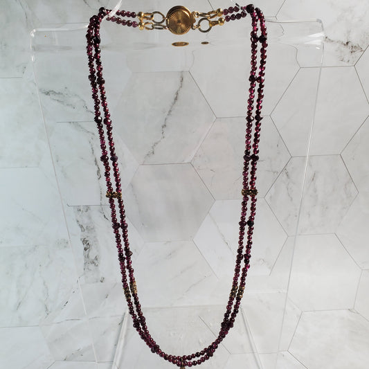 Red beaded necklace with a gold clasp on a marble surface