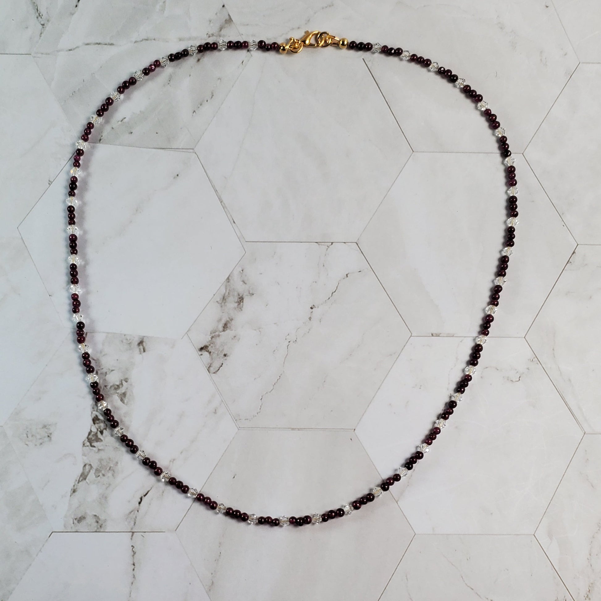 Garnet and crystal gemstone necklace on a marble tile