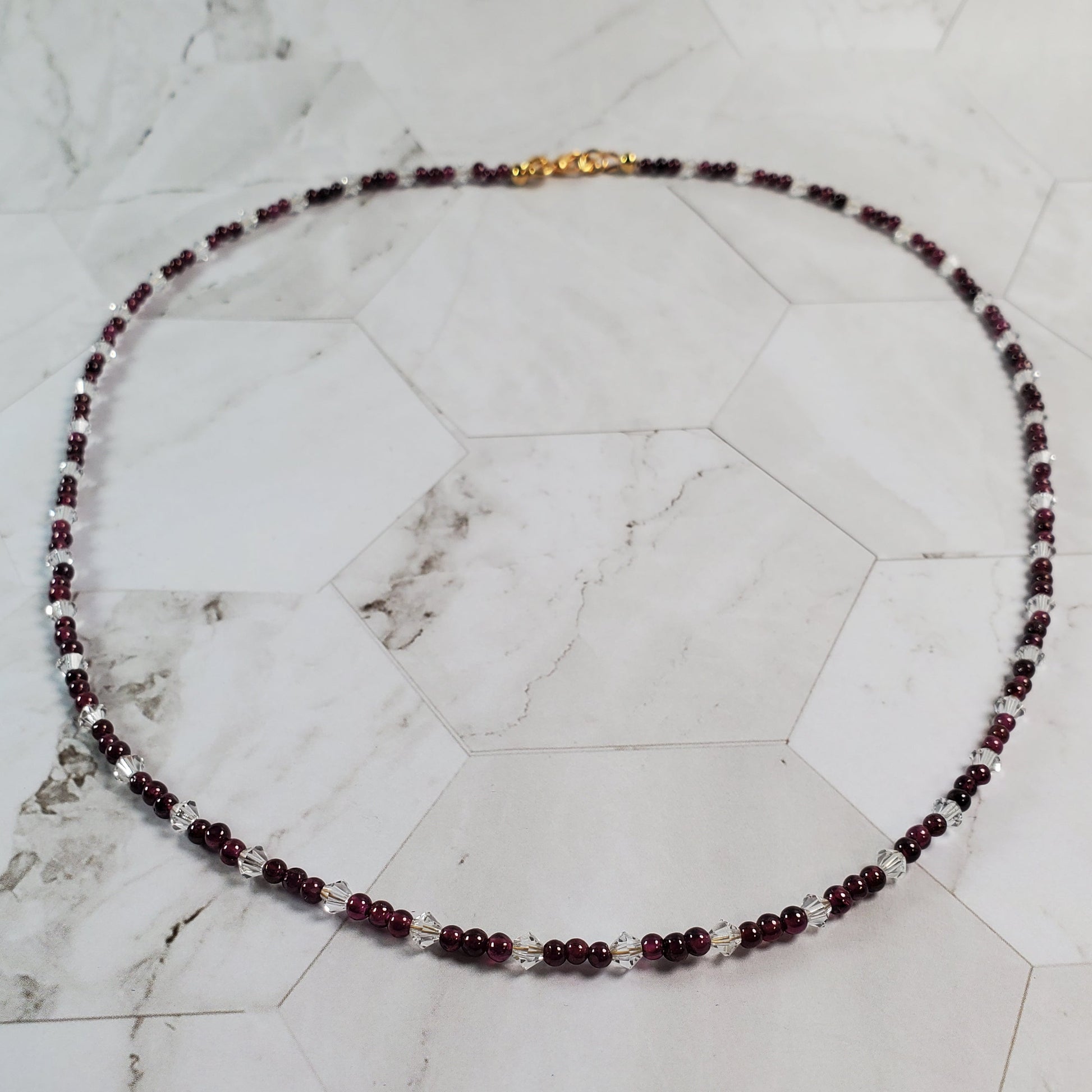 Necklace with red beads and a gold clasp on a marble surface