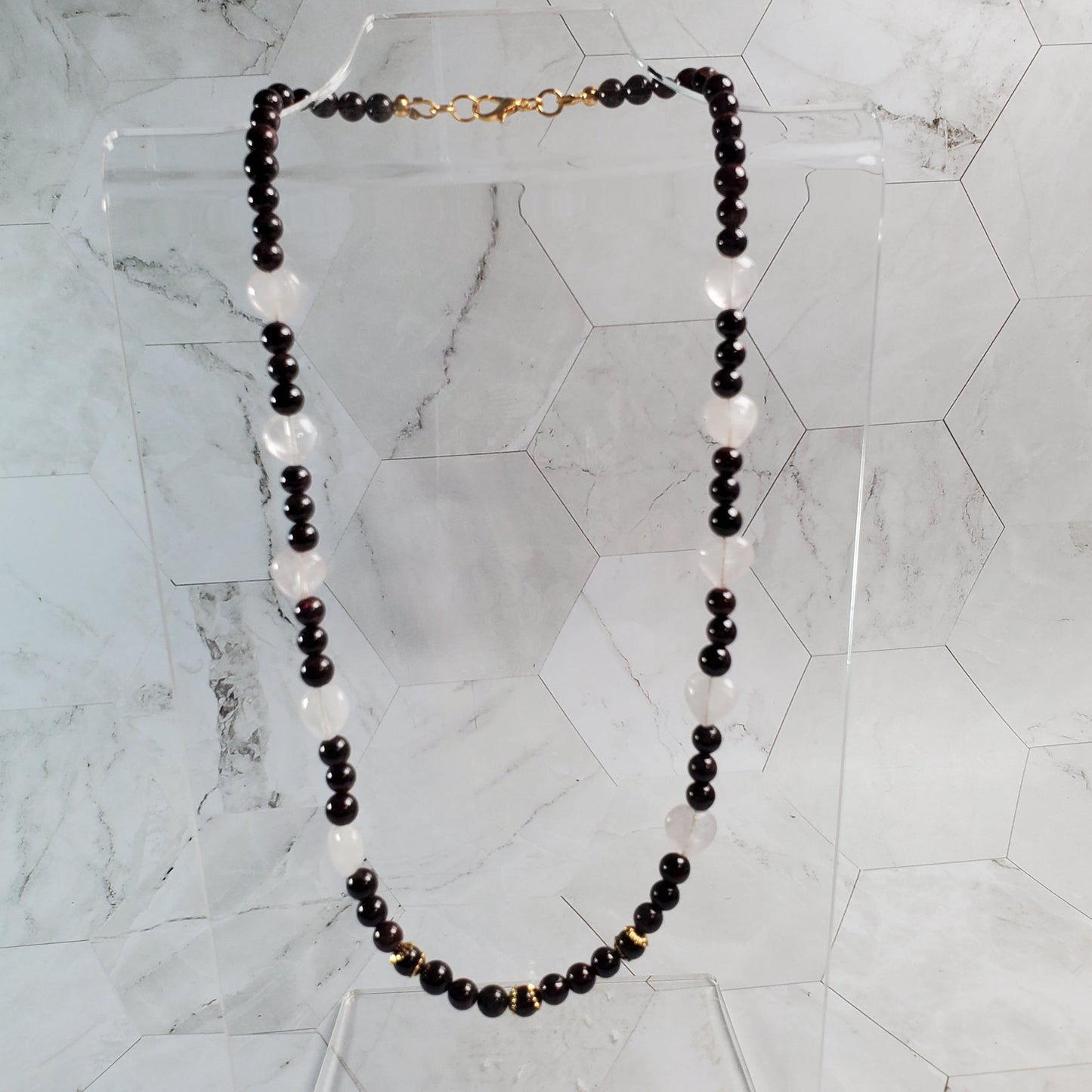 Dark red beaded necklace on a marble surface