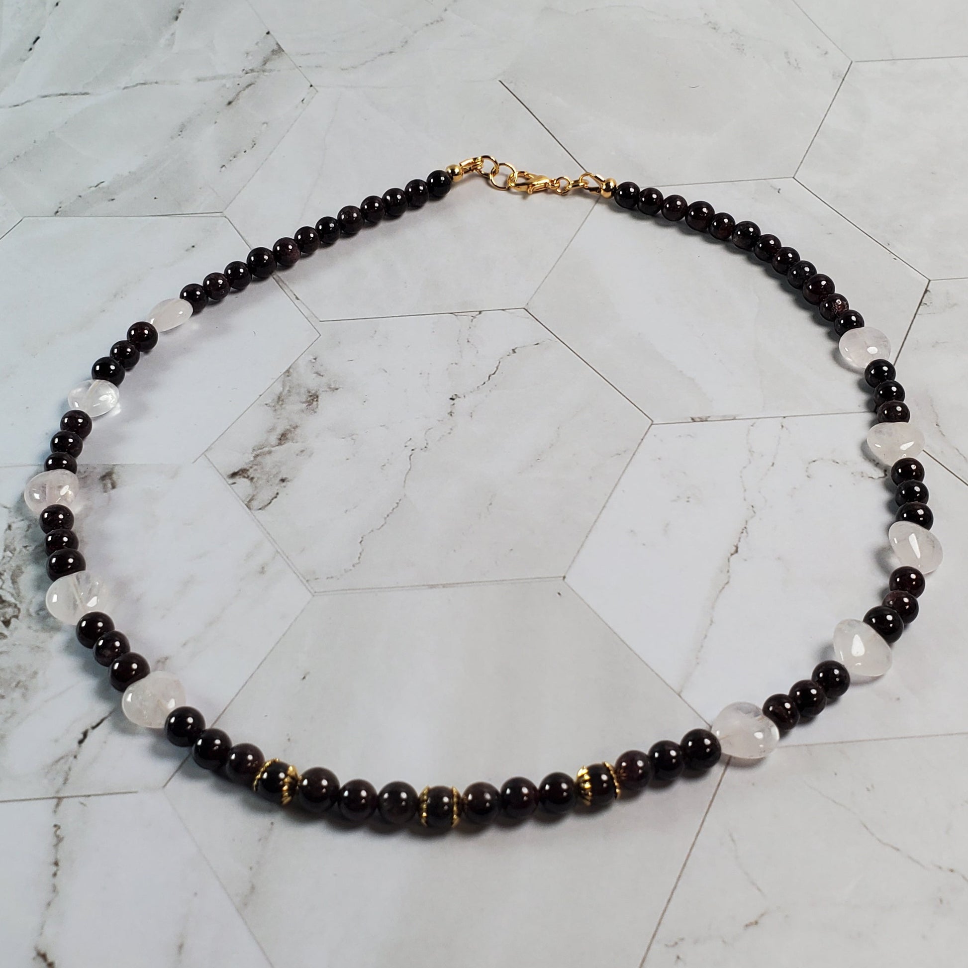 Necklace with dark red and pink beads on a marble surface