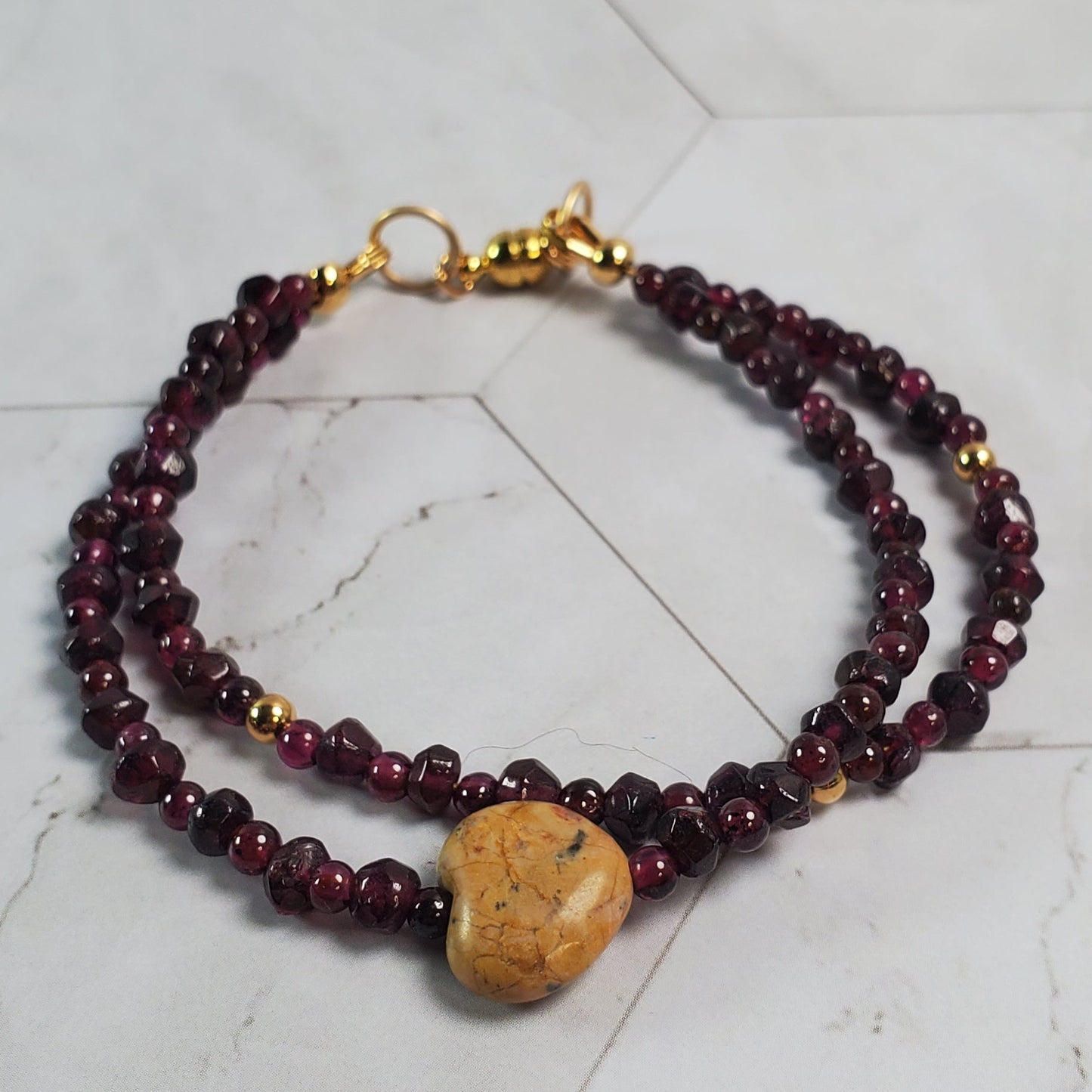 Beaded bracelet with a gold clasp on a marble surface