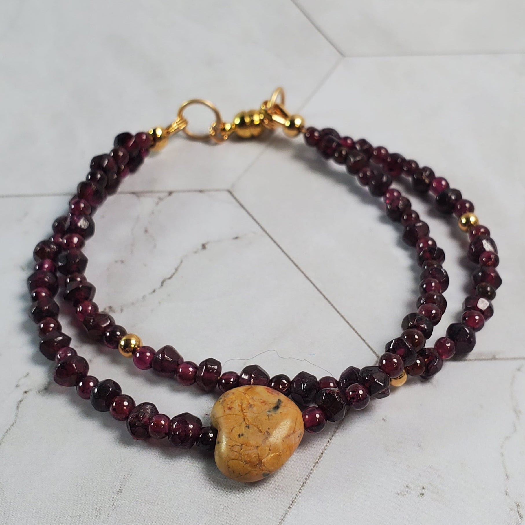 Beaded bracelet with a gold clasp on a marble surface