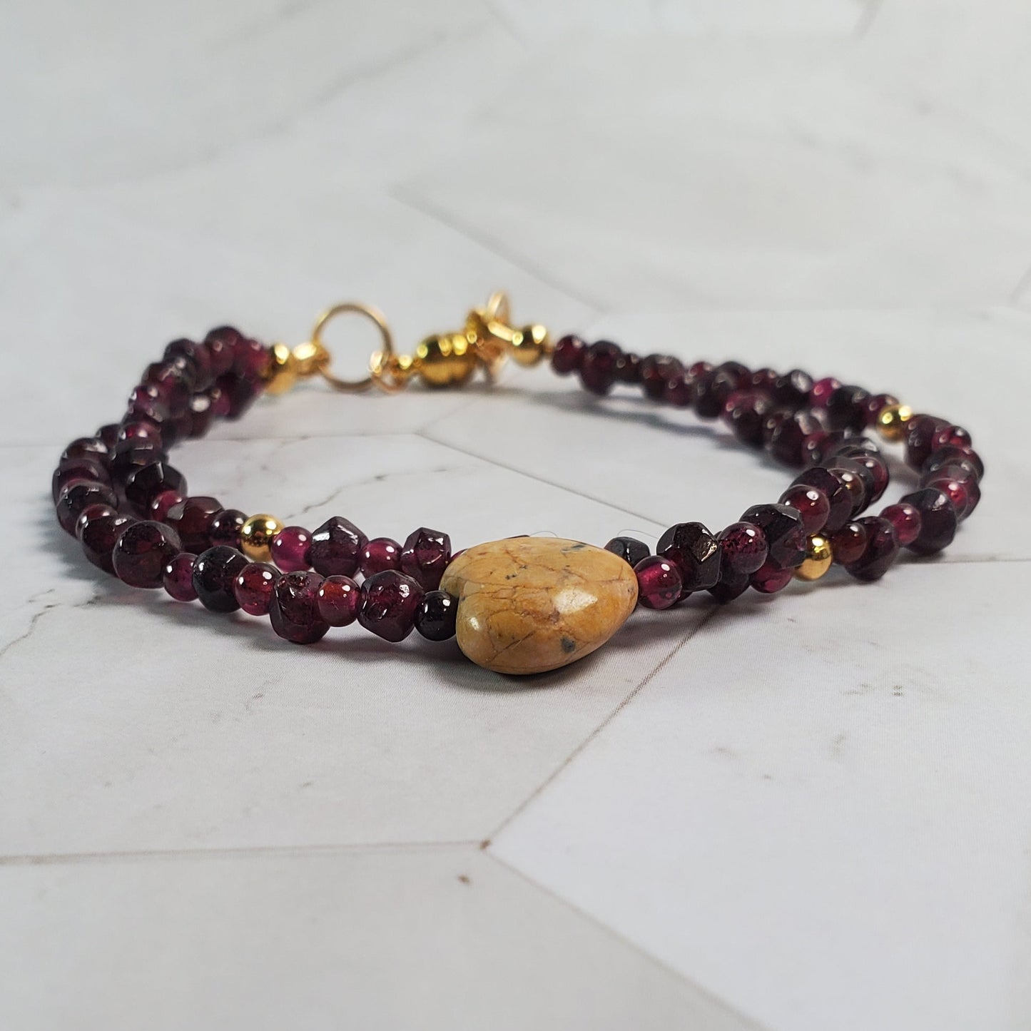 Beaded bracelet with a wooden heart charm on a marble surface