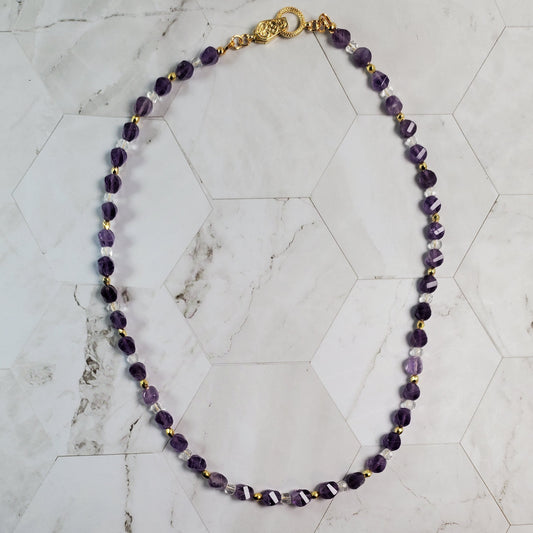 Purple beaded necklace on a marble surface