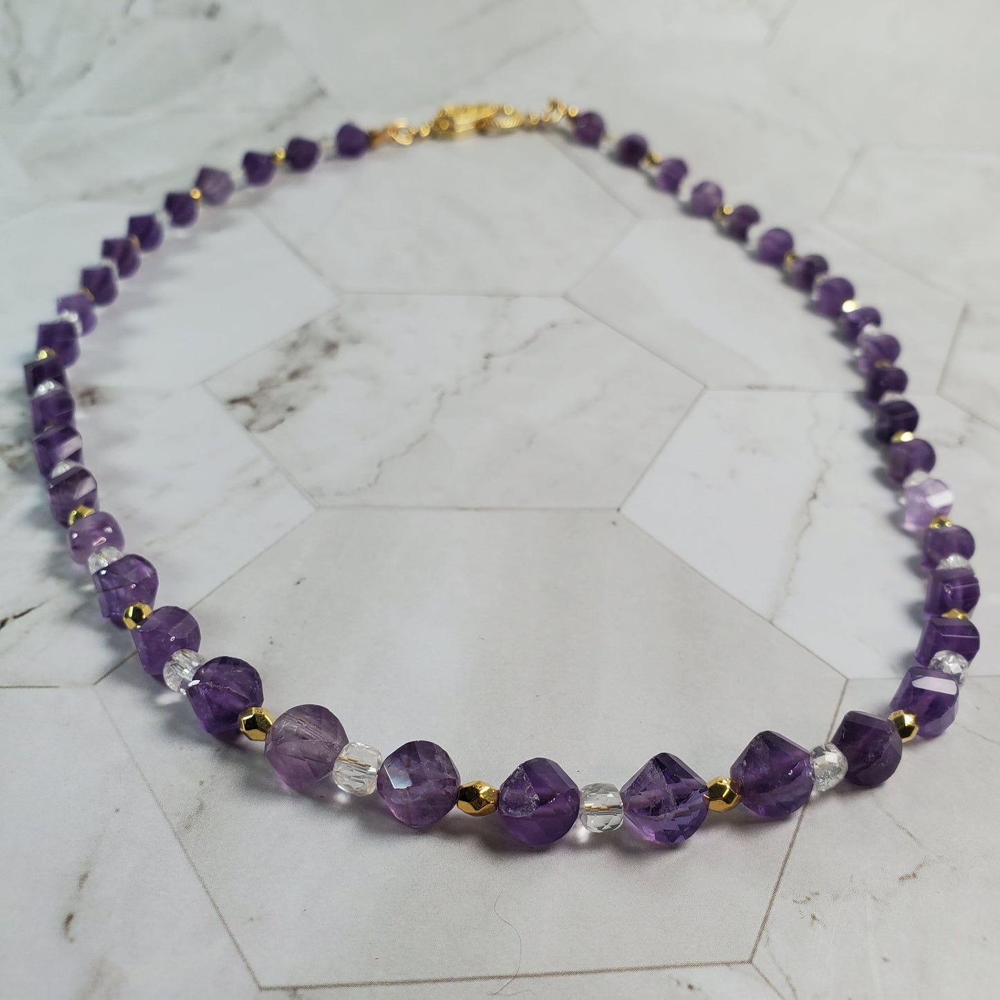 Necklace with purple and clear beads on a marble surface