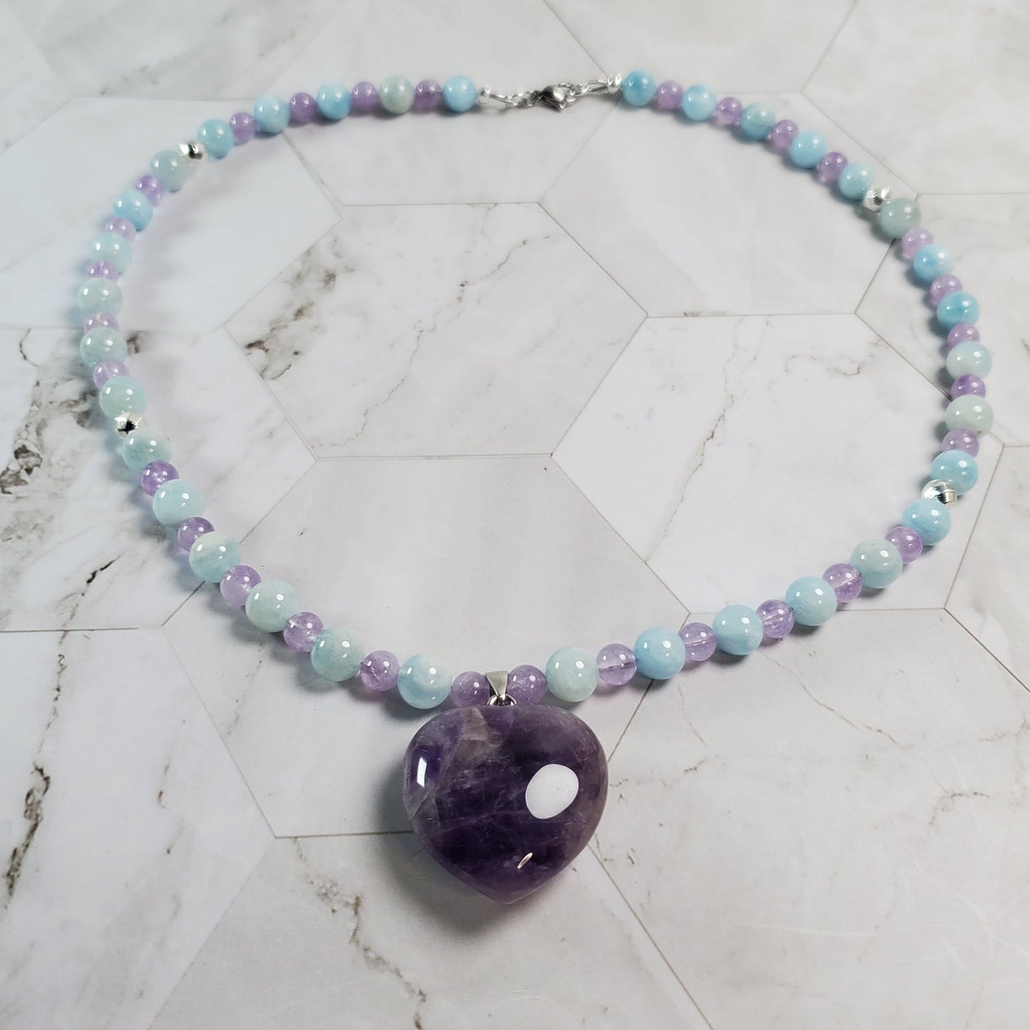 Necklace with colorful beads and a purple stone on a marble surface