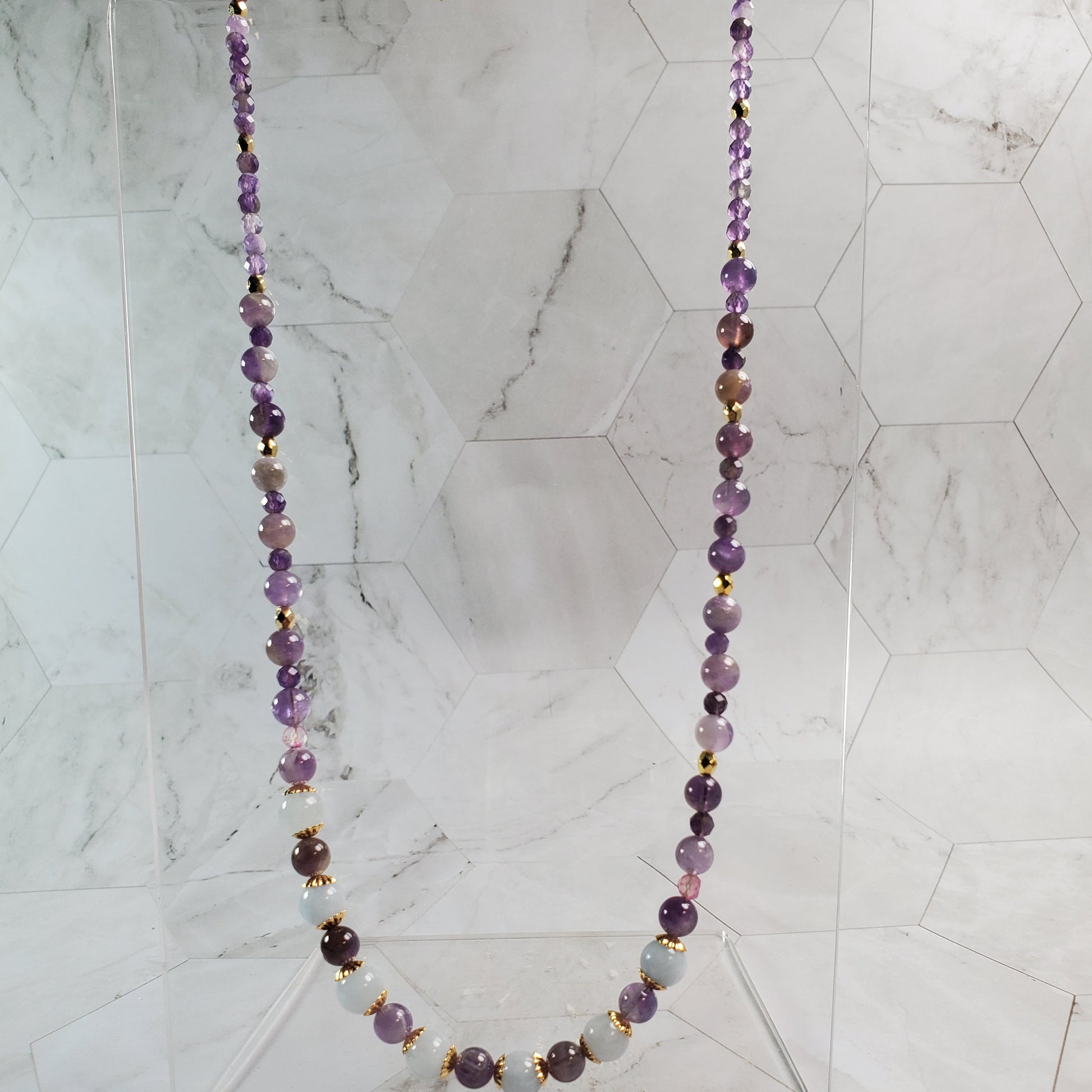 Necklace with purple and blue beads on a marble background