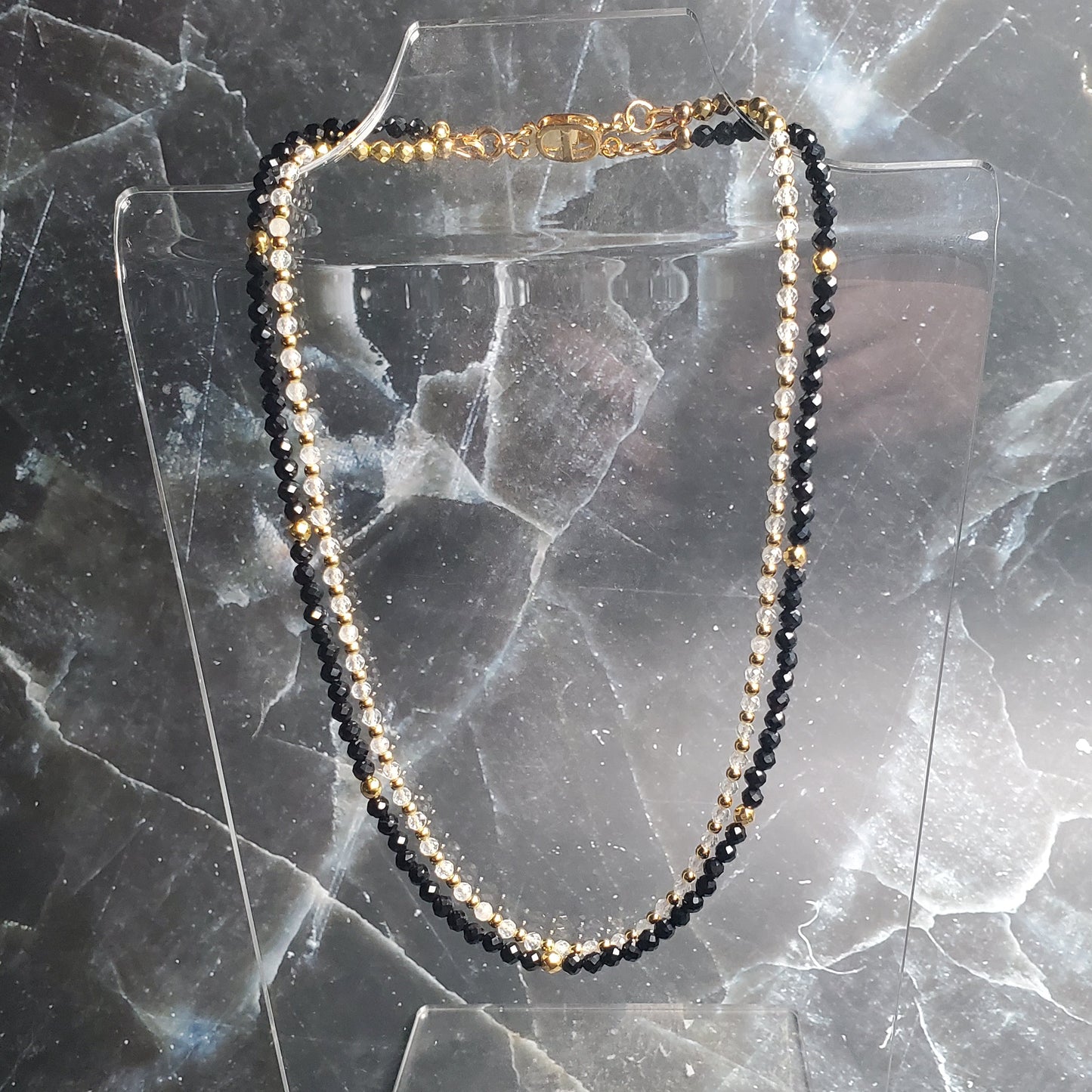 Necklace with black and gold beads on a marble surface