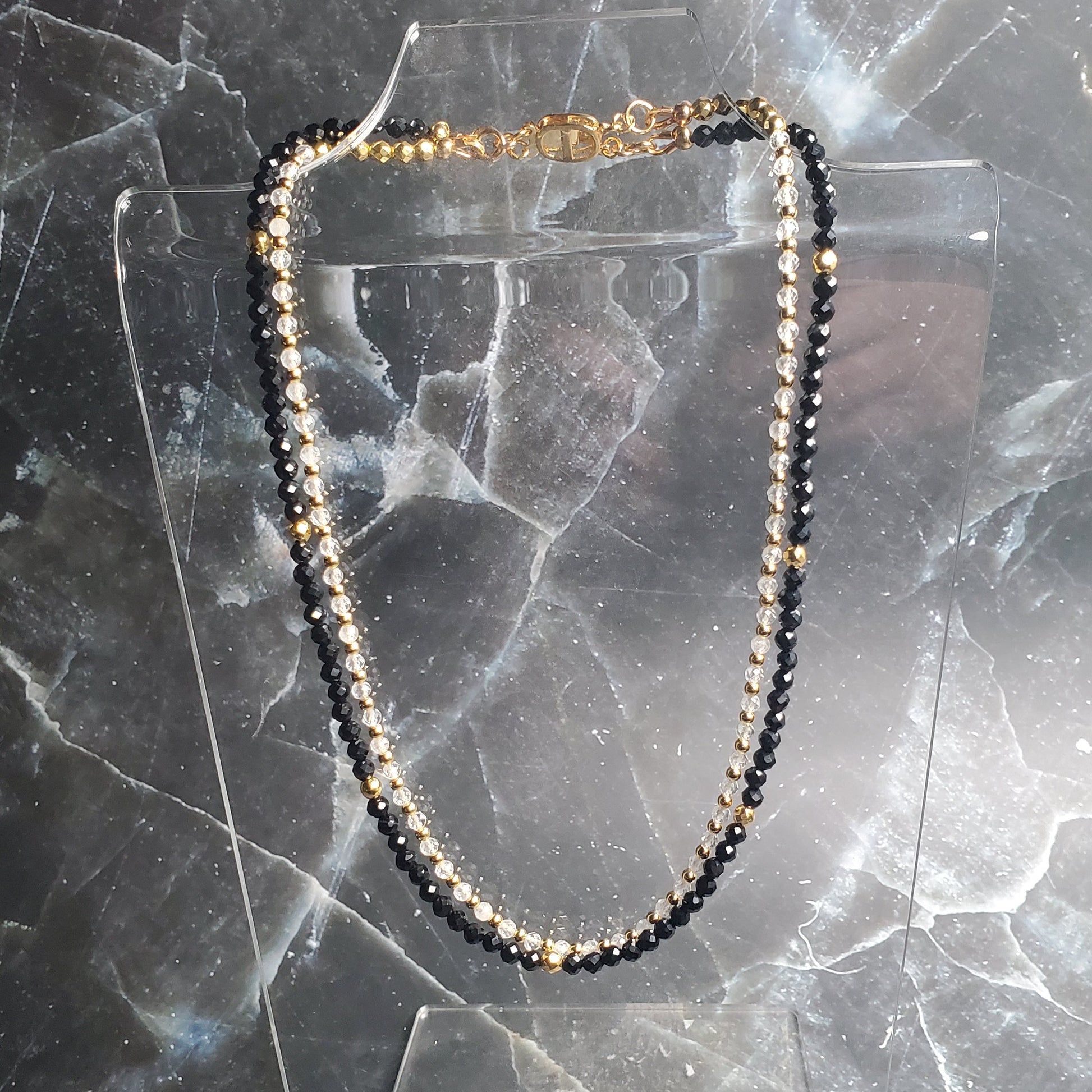 Necklace with black and gold beads on a marble surface