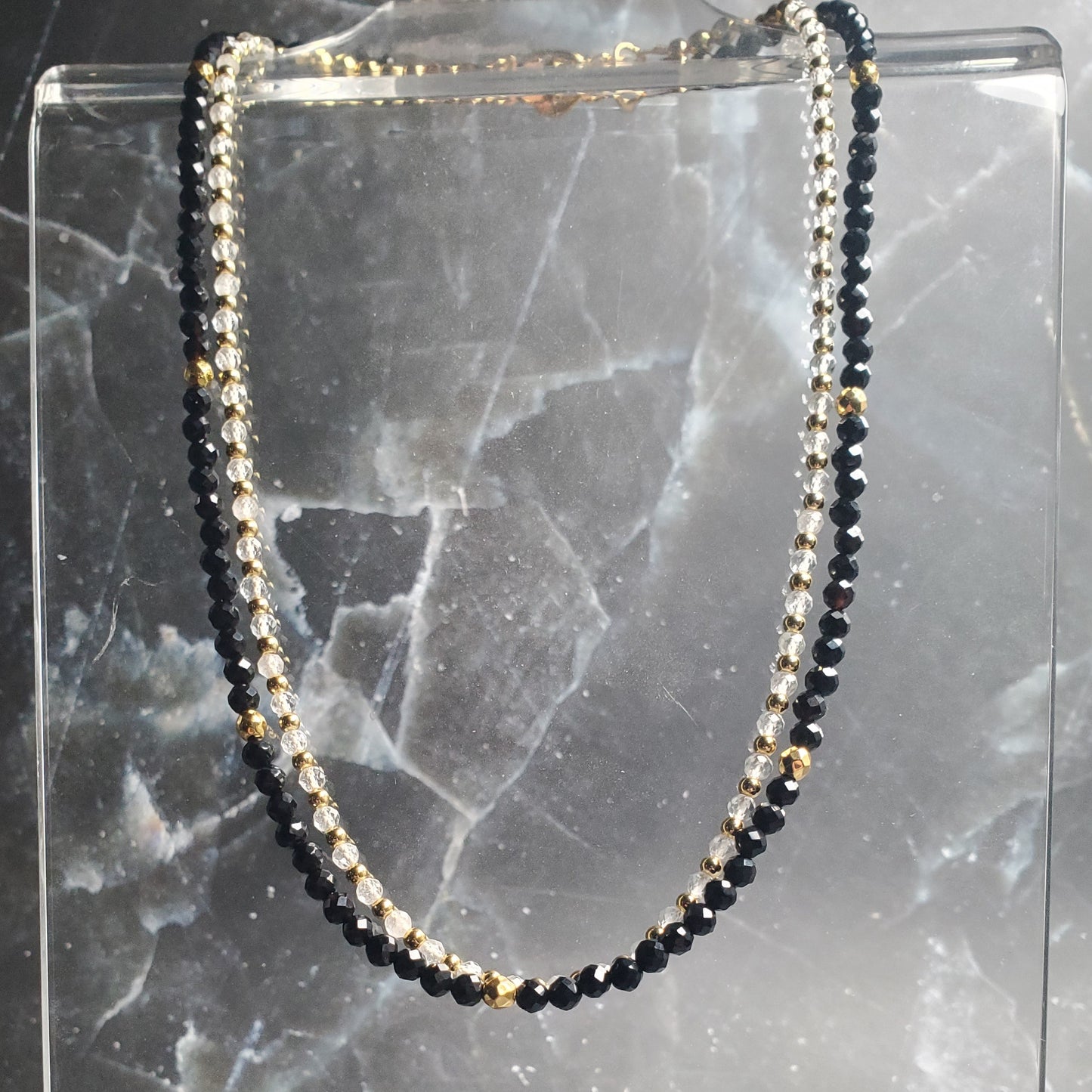 Black beaded necklace on a marble surface