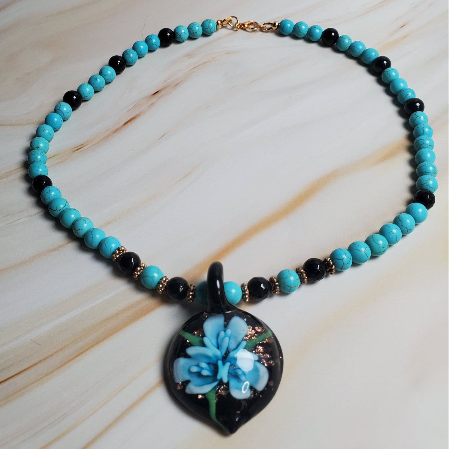 Beaded necklace with a floral pendant on a light wood surface