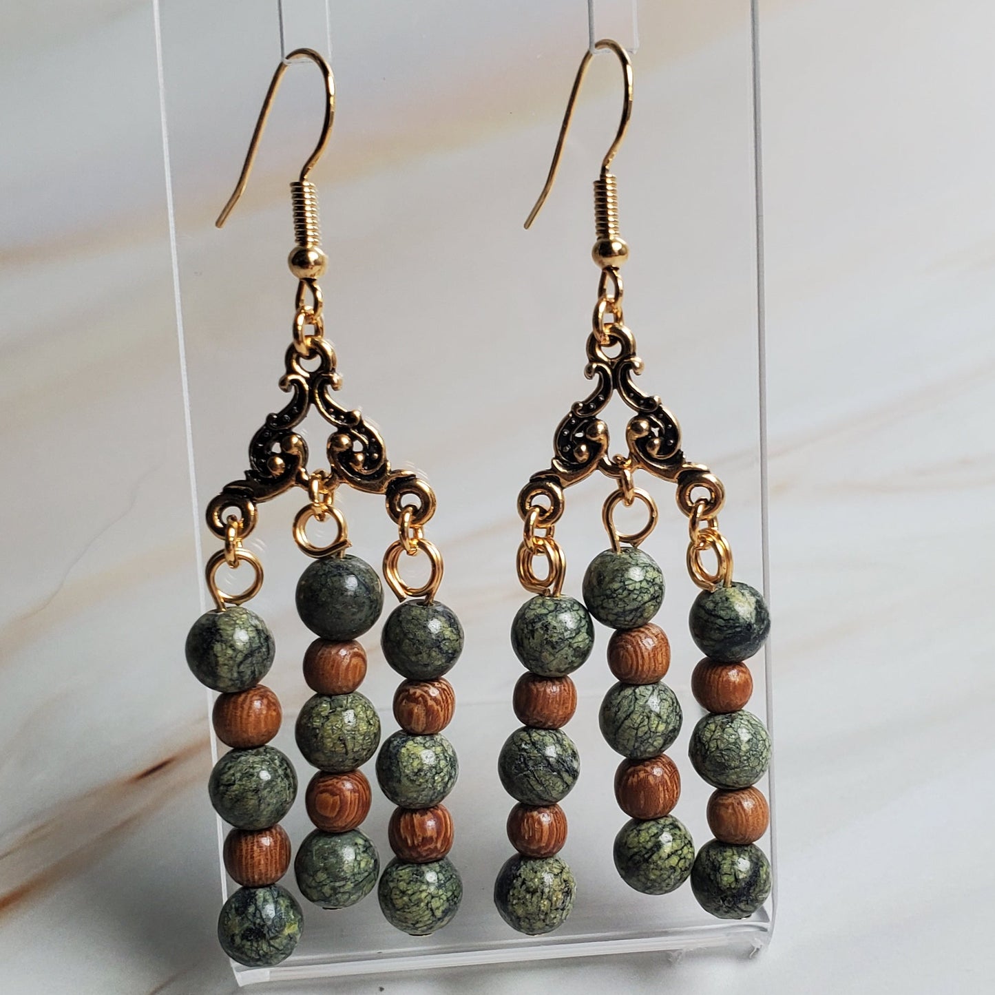 Beaded earrings on a clear stand against a marble background