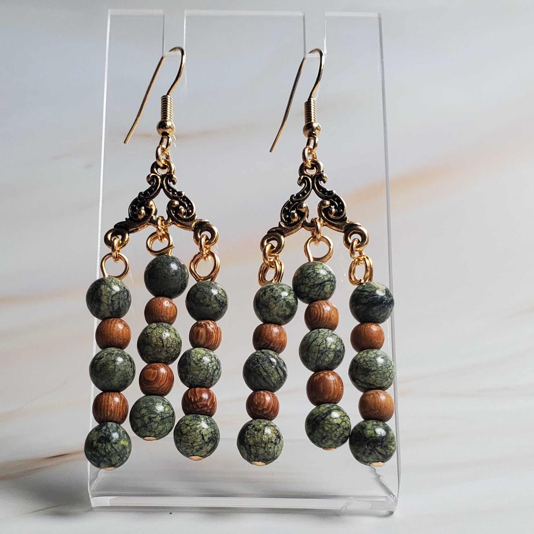 Beaded earrings on a clear stand against a marble background