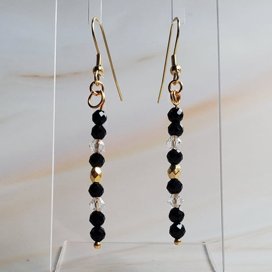Pair of beaded earrings on a clear stand against a marble background
