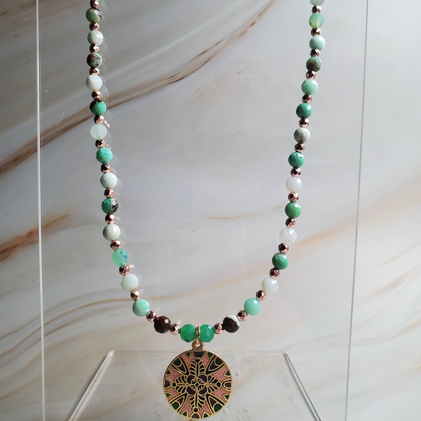 Necklace with green beads and a decorative clasp on a marble background