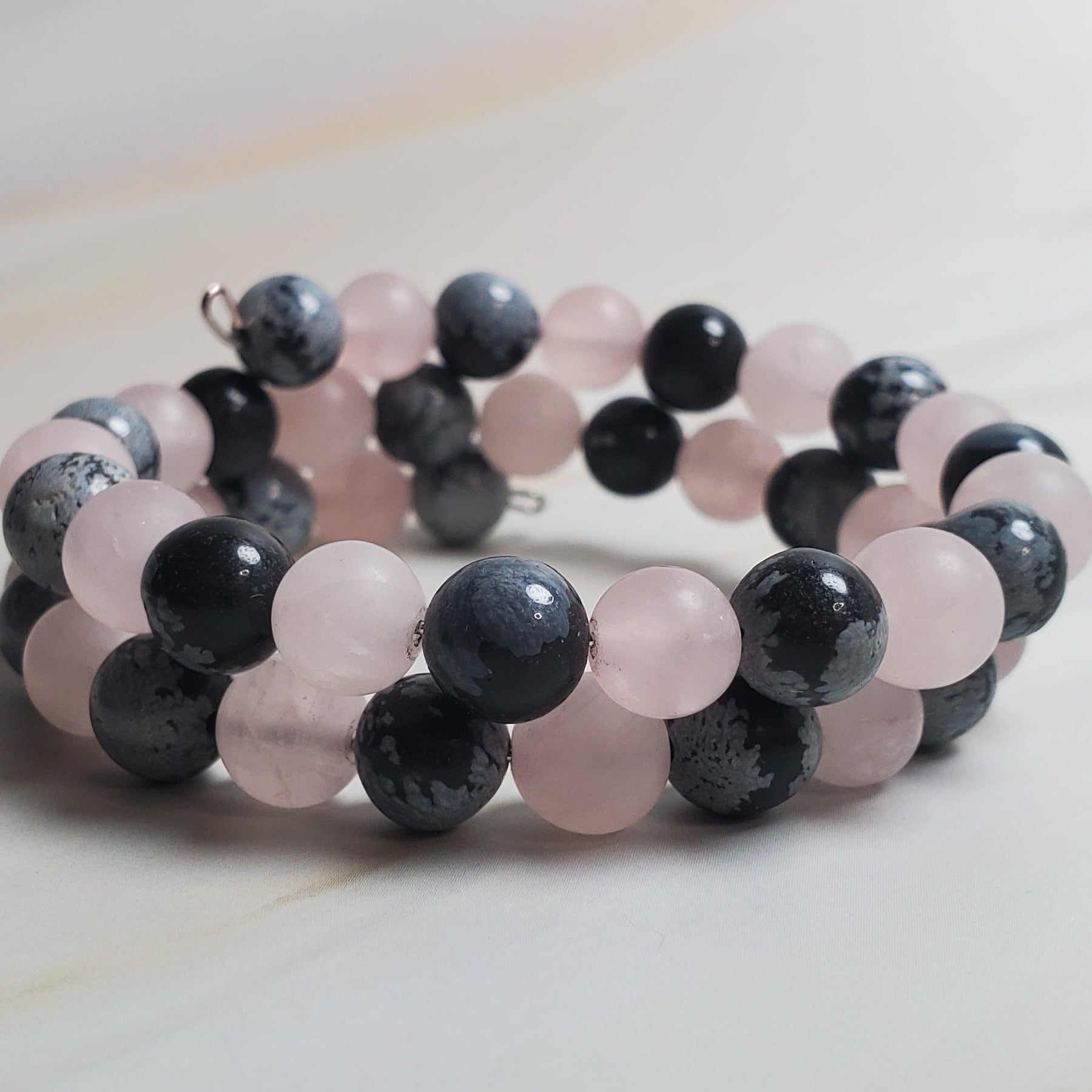 Beaded bracelet with pink and black beads on a light wooden surface