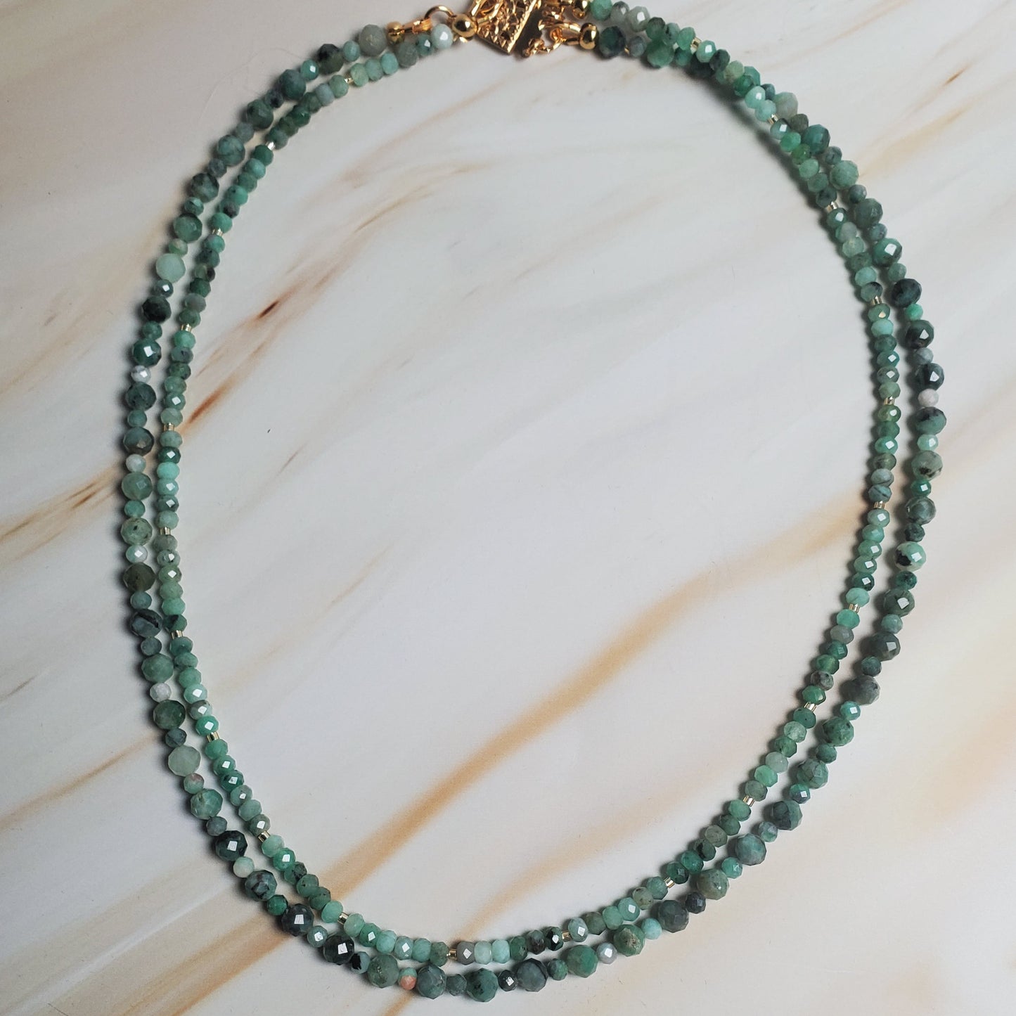 Green beaded necklace on a light wood surface
