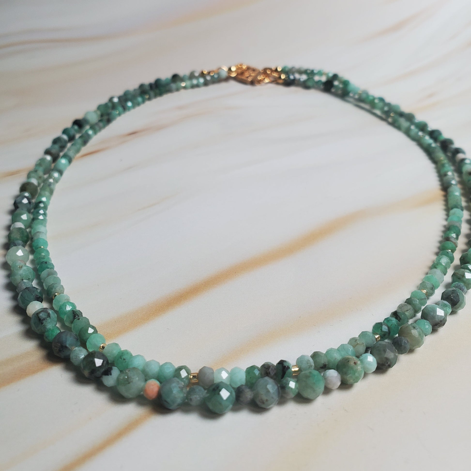 Beaded necklace with green stones on a light background