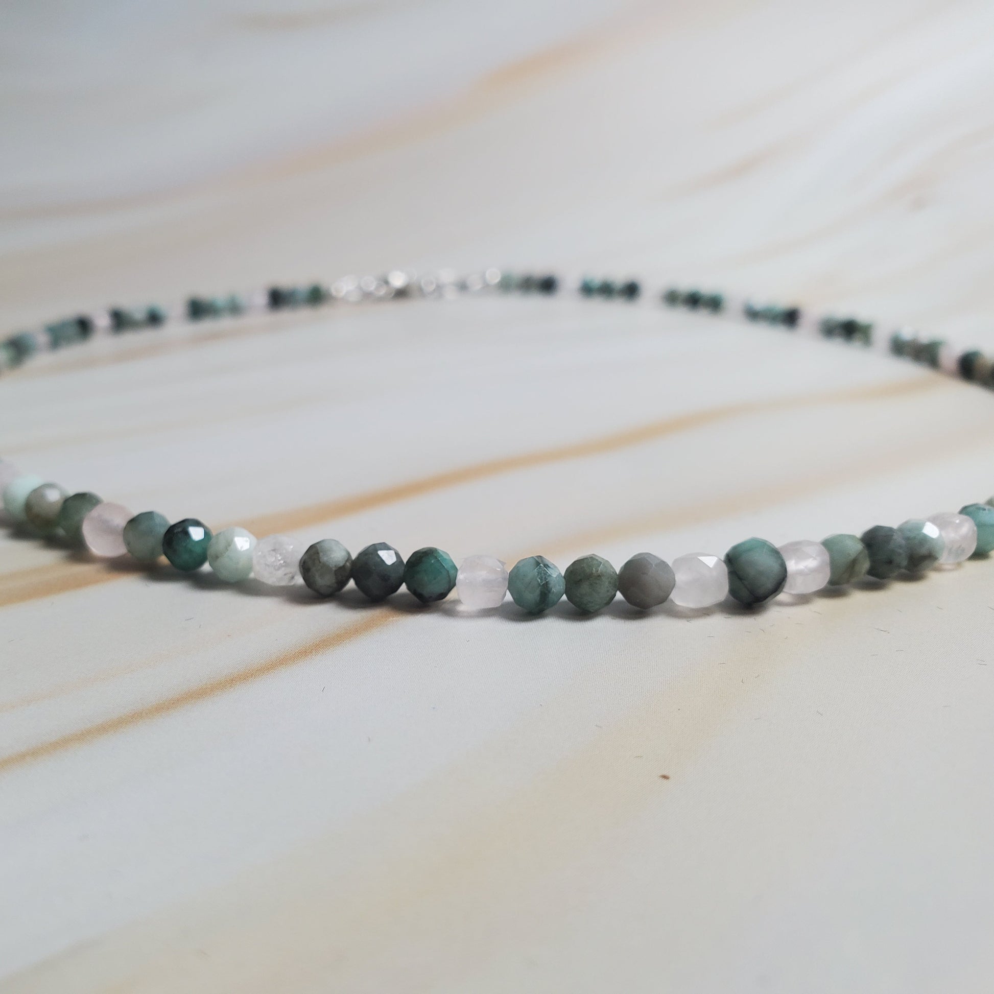 Necklace with green and white beads on a light wooden surface