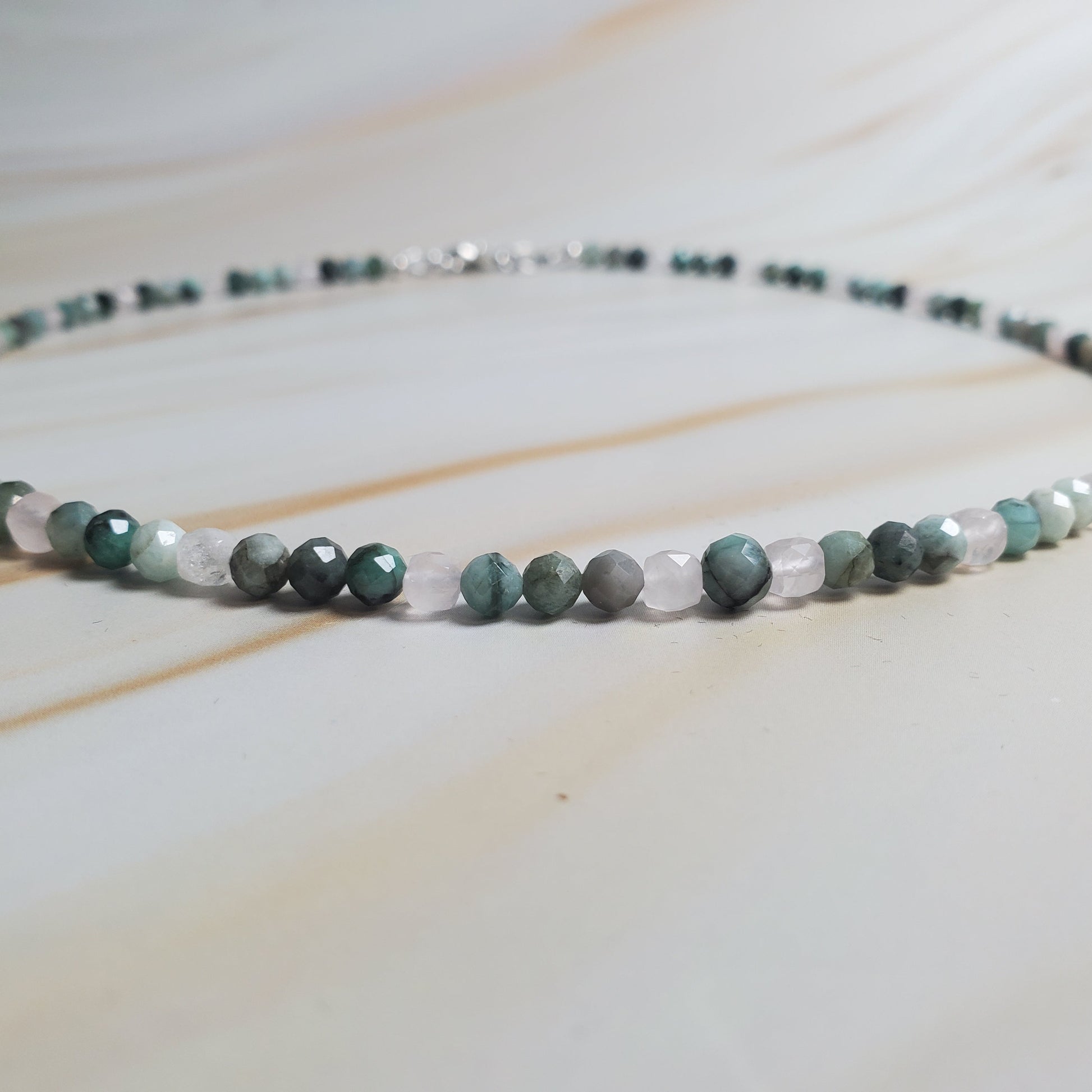 Beaded necklace with green and white beads on a light wooden surface