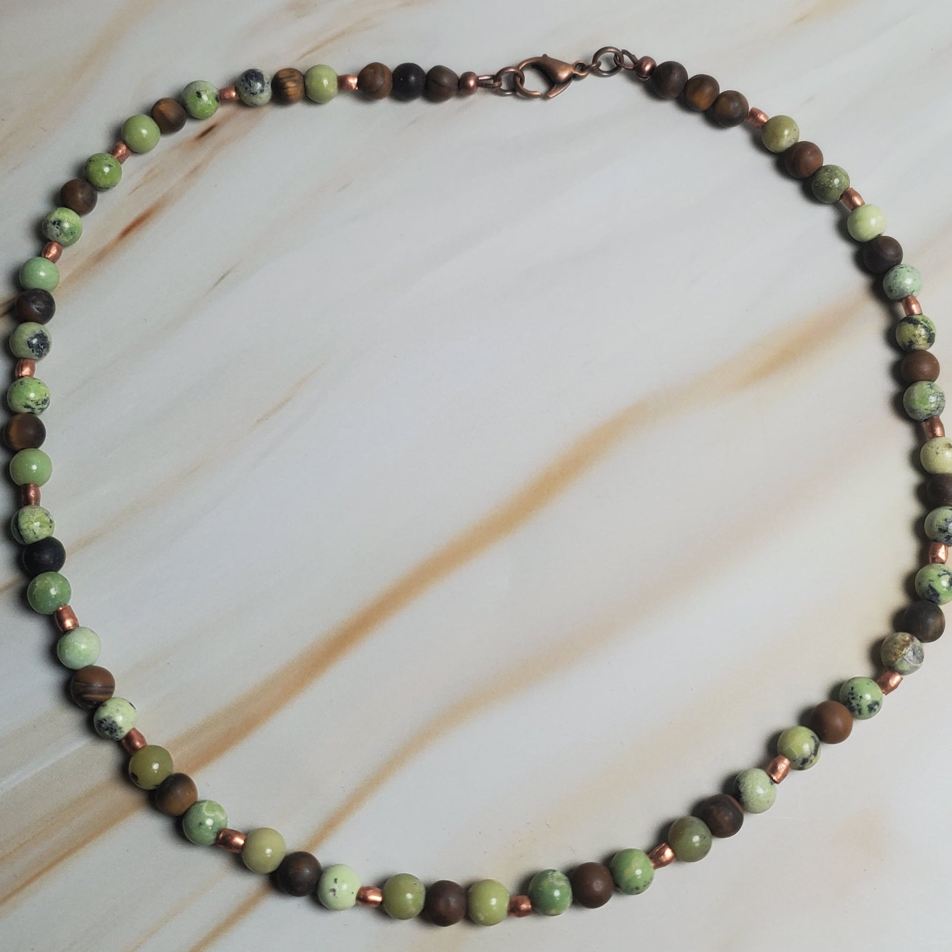 Necklace with green and brown beads on a beige fabric background