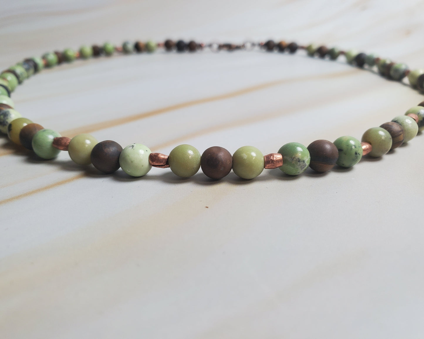 Necklace with green and brown beads on a light background