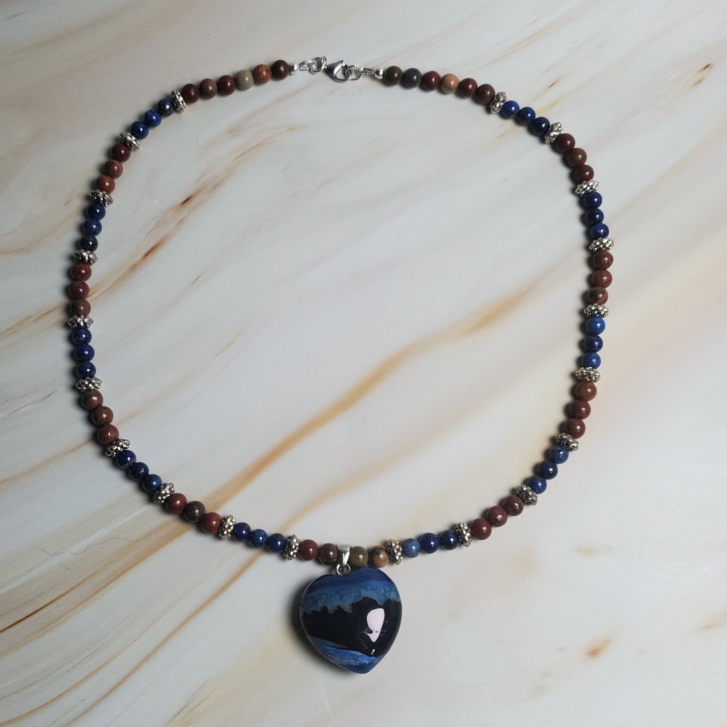 Beaded necklace with a blue pendant on a marbled surface