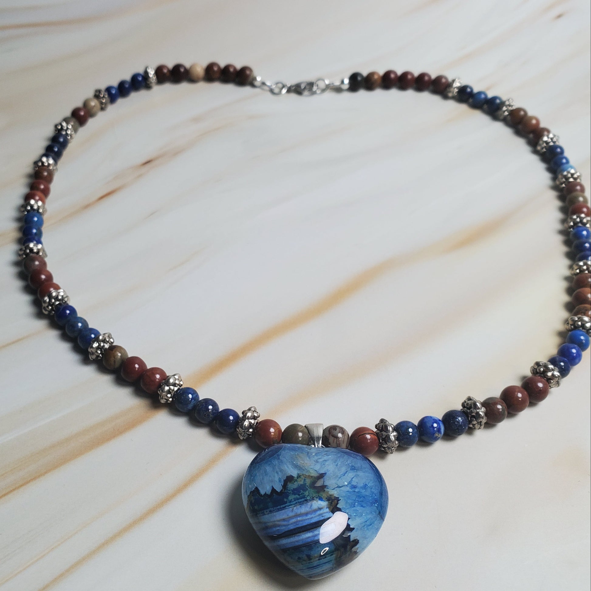 Necklace with blue pendant and multicolored beads on a light wood surface