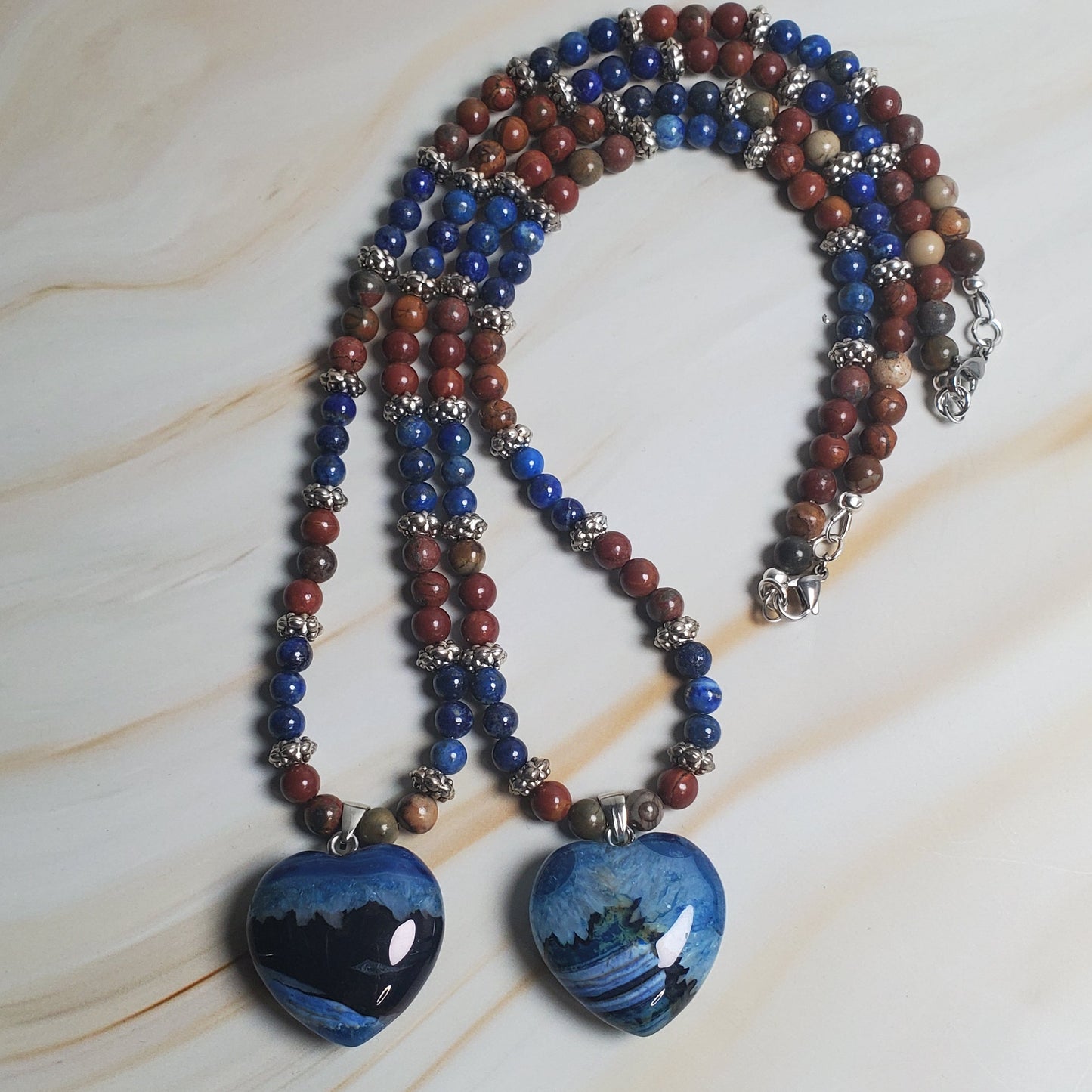 Multicolored beaded necklace with blue pendant on a marble surface