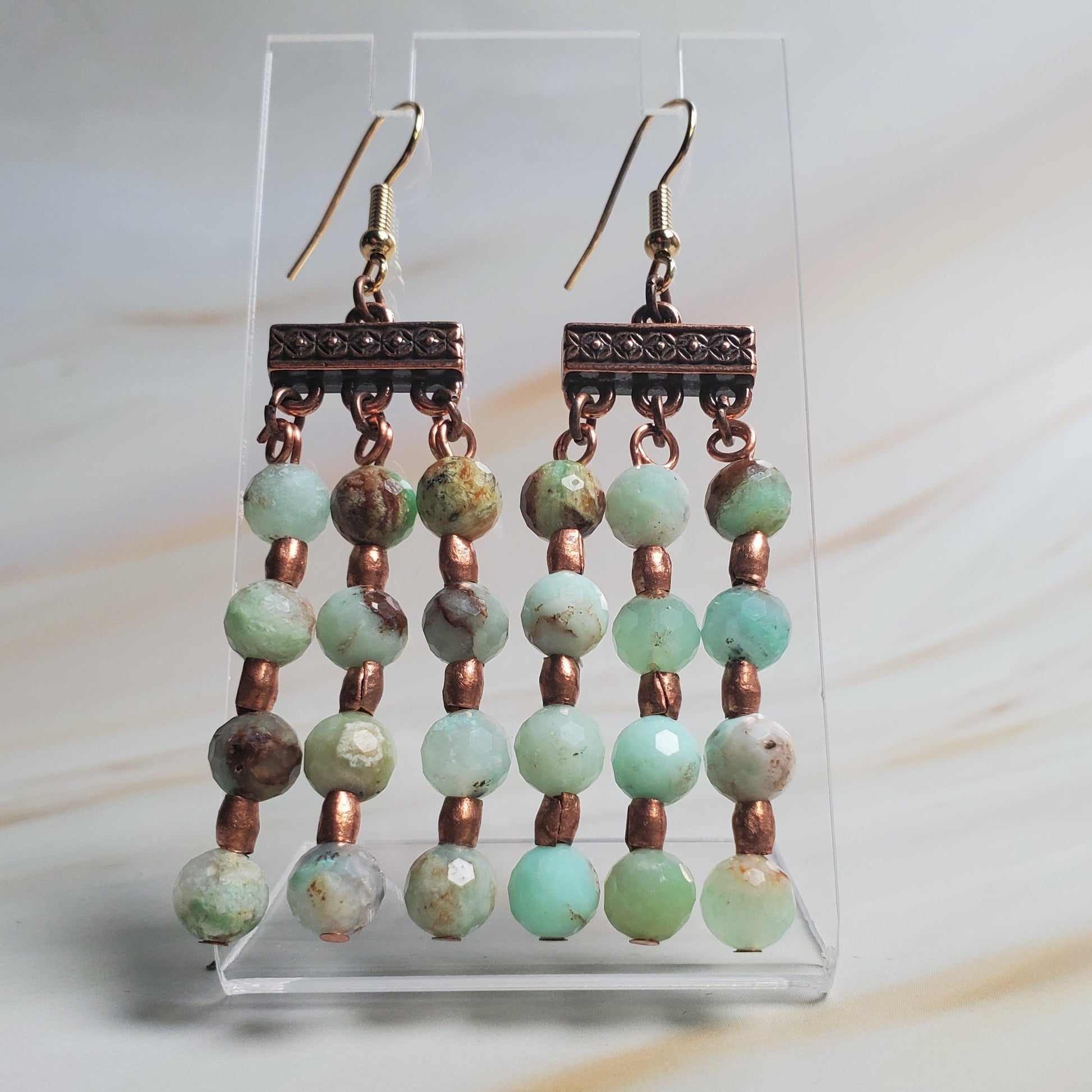 Pair of beaded earrings on a clear stand with a light background