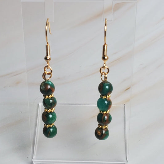 Pair of earrings on a clear stand against a marble background