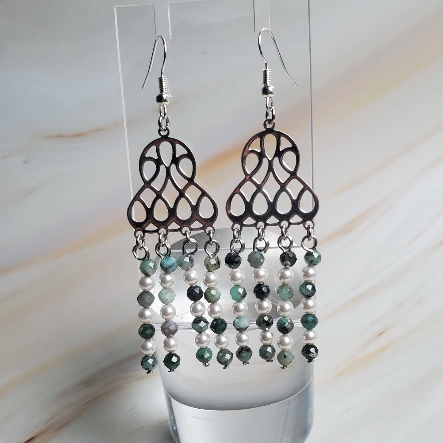 Pair of earrings on a clear stand against a light background