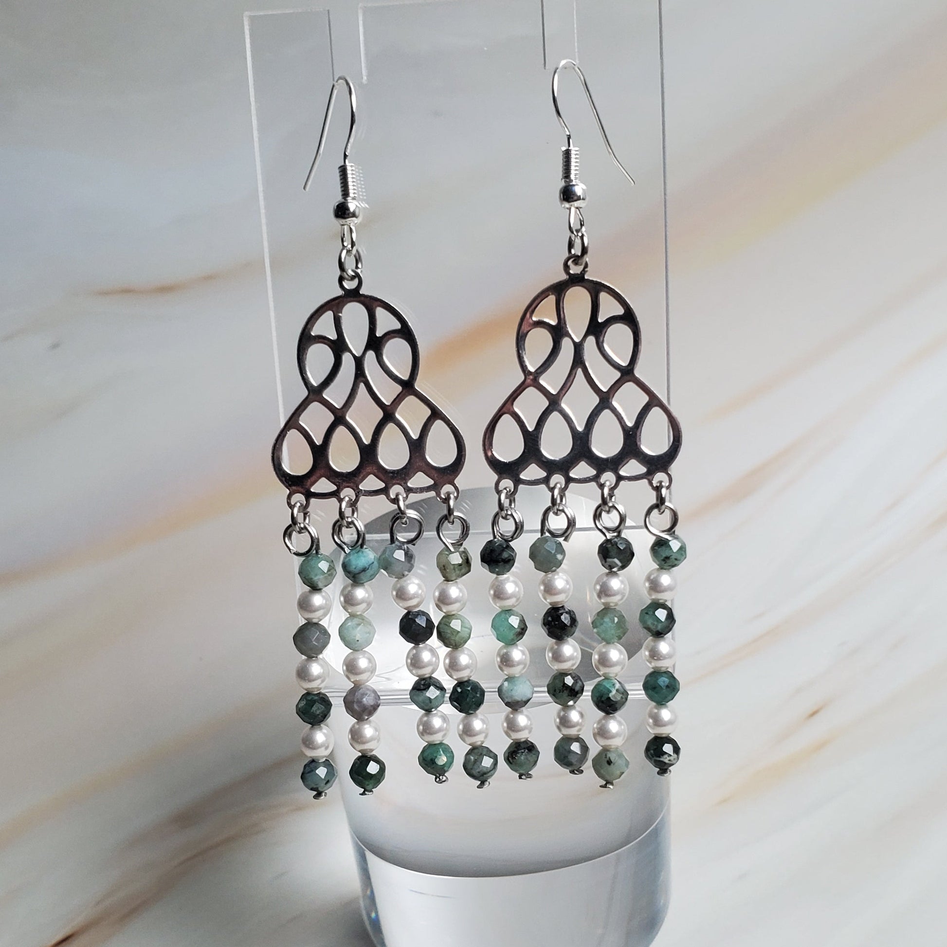 Pair of earrings on a clear stand against a light background