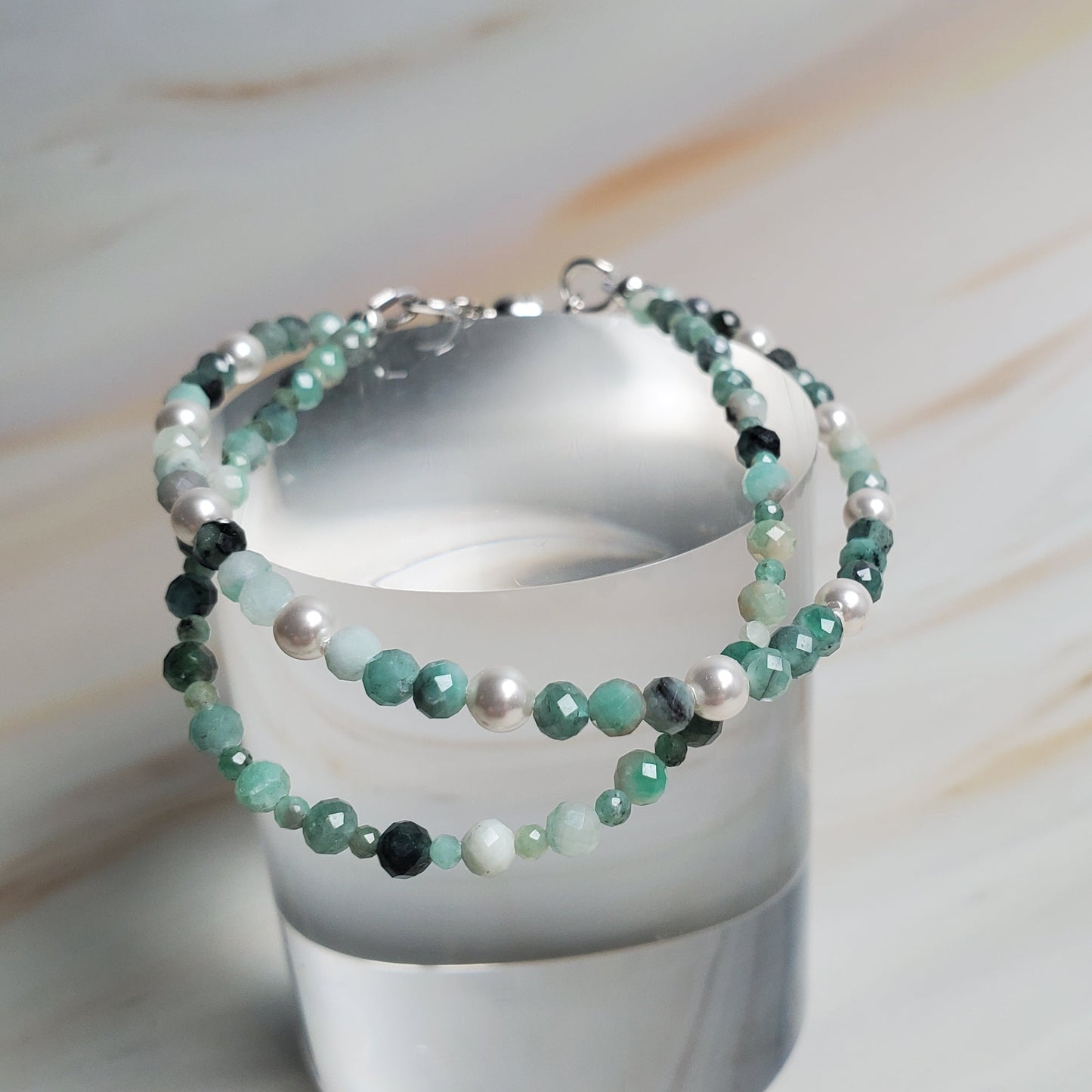 Beaded bracelet on a white cylindrical stand against a marble background