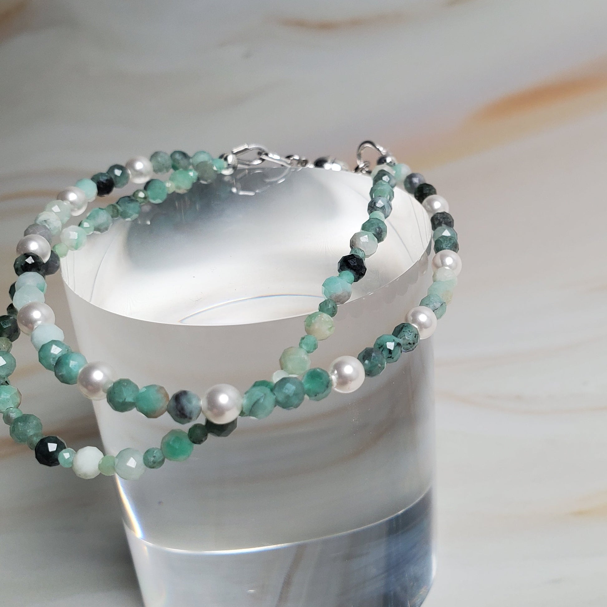 Stacked beaded bracelet on a cylindrical silver holder against a marble background