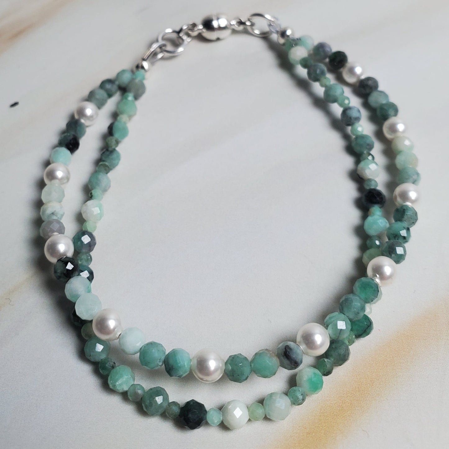 Beaded bracelet with green and white stones on a marble surface