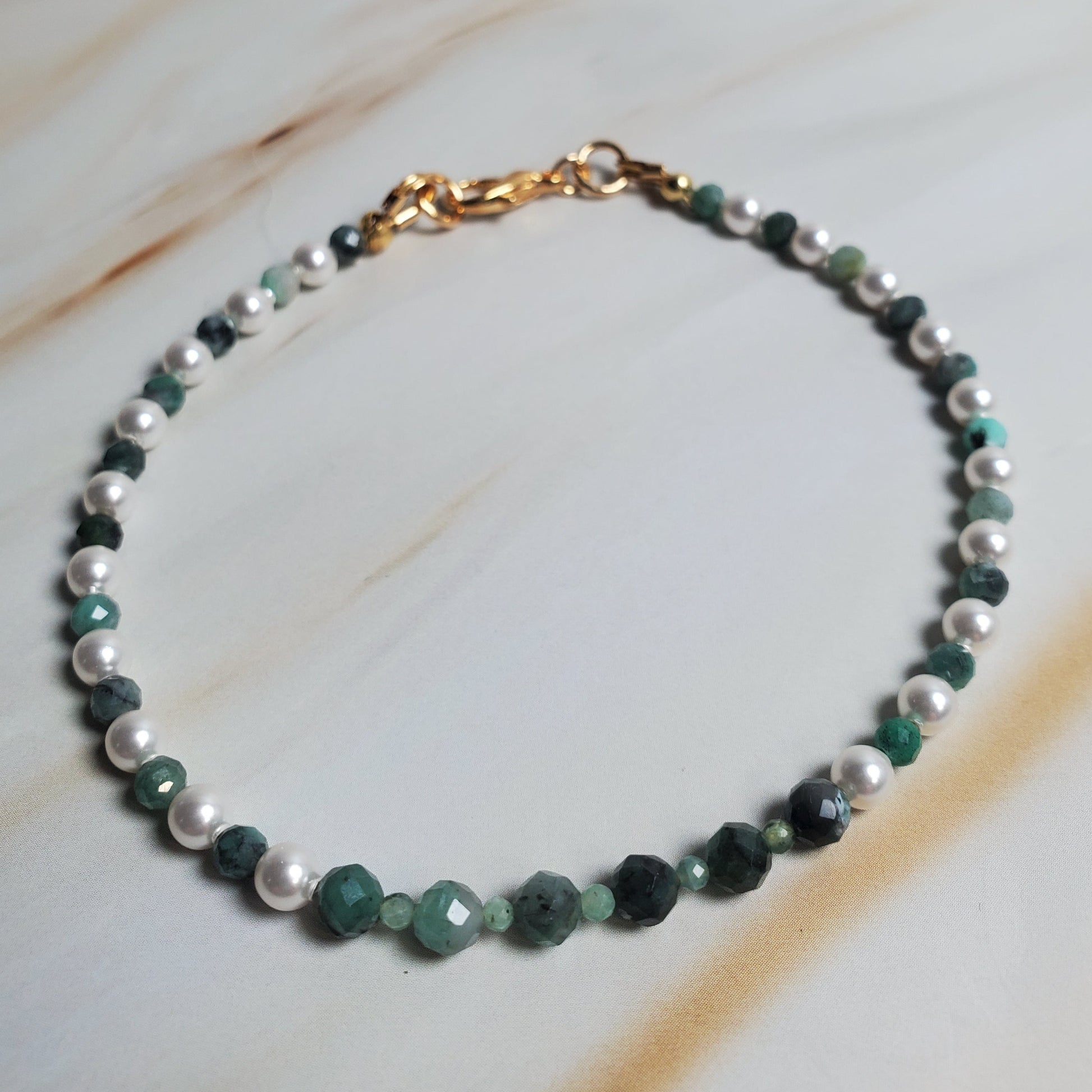 Beaded bracelet with green and white beads on a marble surface