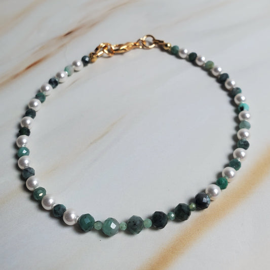 Beaded bracelet with green and white beads on a marble surface