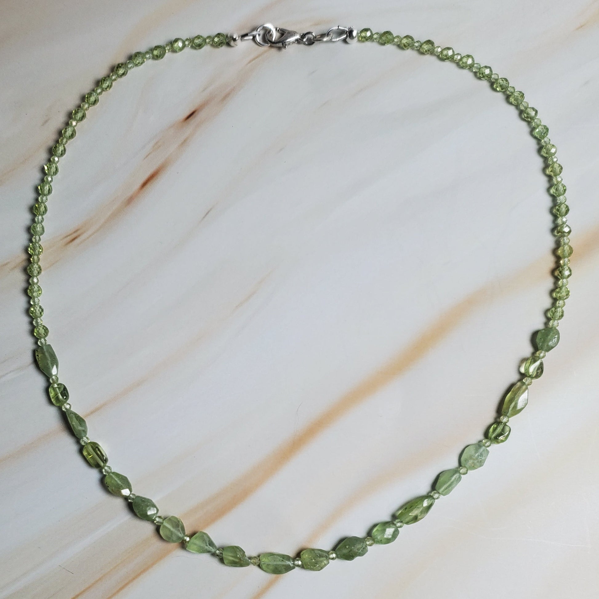 Green beaded necklace on a textured beige surface