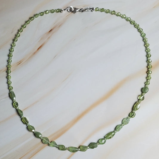 Green beaded necklace on a textured beige surface